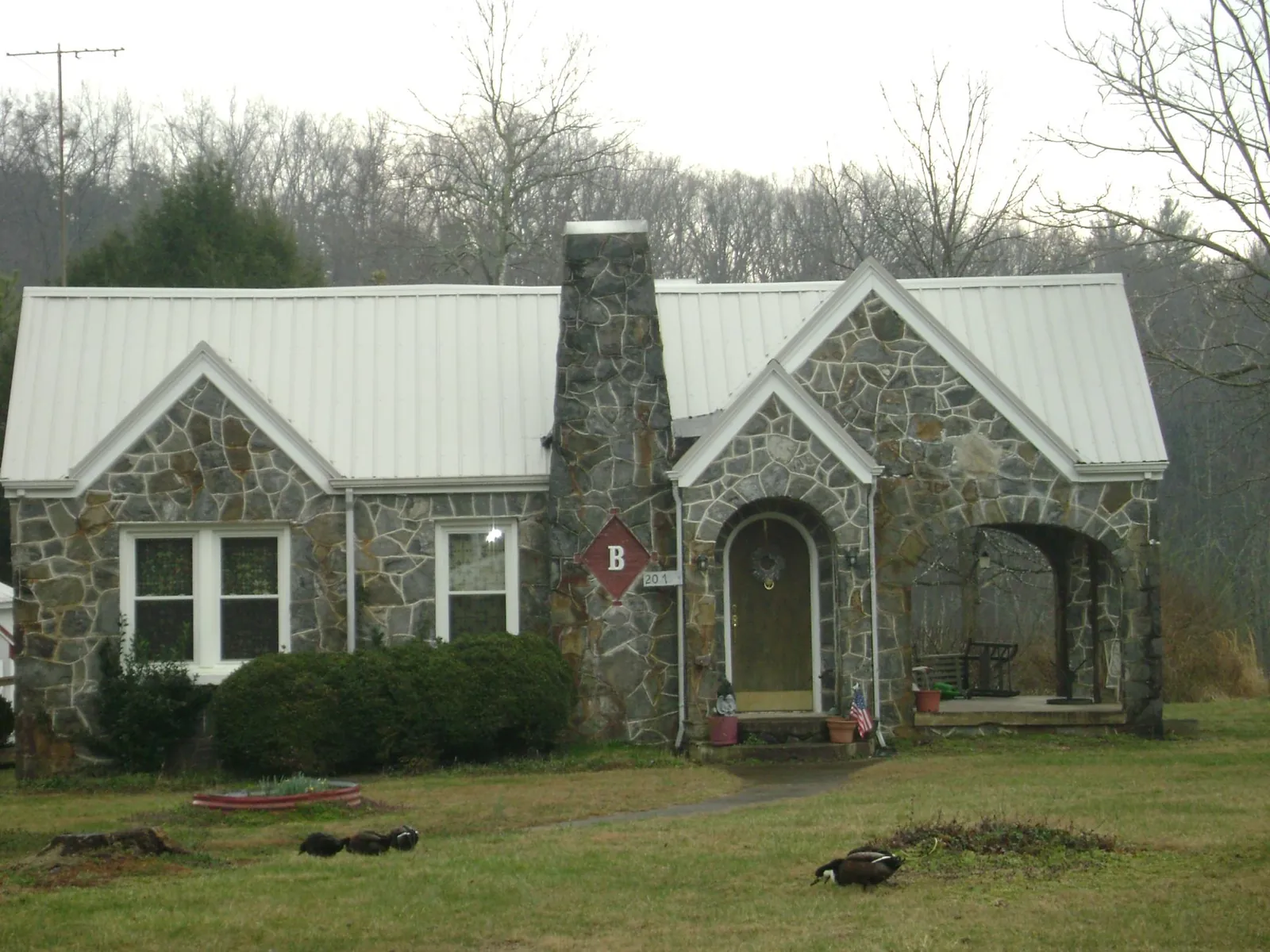 White metal roof on a stone cottage with steep gables in Mendon